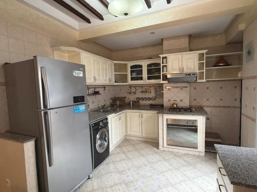 a kitchen with a stainless steel refrigerator and white cabinets at Grand 3 pièces de standing, confort premium in Casablanca