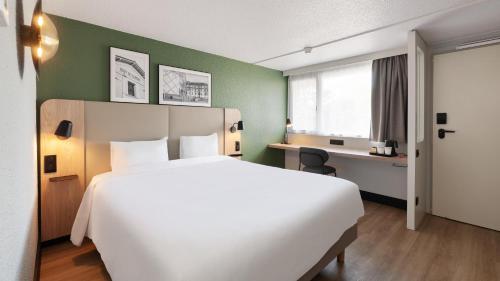 een hotelkamer met een groot wit bed en een bureau bij Campanile NATURE - Toulouse Nord L'Union in LʼUnion