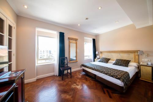 a bedroom with a bed and two windows at Soho Boutique Salamanca in Salamanca