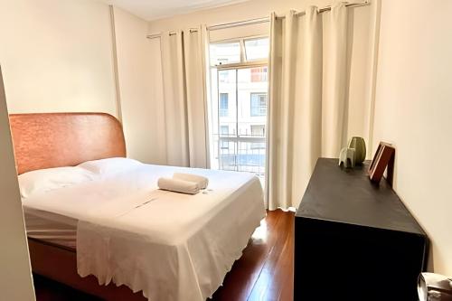 a bedroom with a bed with white sheets and a window at Village in Viçosa