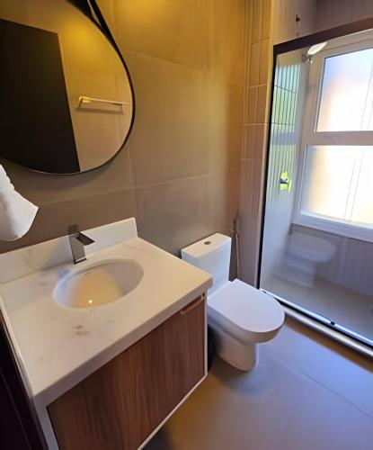 a bathroom with a sink and a toilet and a mirror at Tribeca Gramado 12 in Gramado