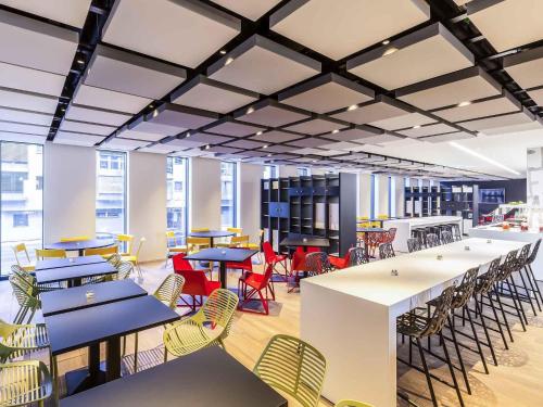 a large room with tables and chairs and windows at ibis Styles Basel City in Basel