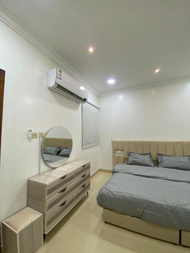 una camera da letto con un letto con specchio e una cassettiera di شقق vip a Al Hofuf