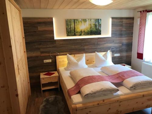een slaapkamer met een bed met een houten muur bij Ferienwohnung Hirtreiter in Lalling