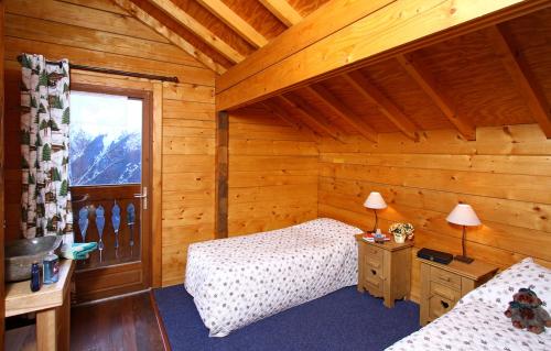 a bedroom with two beds in a log cabin at Odalys Chalet le Soleil Levant in Les Deux Alpes