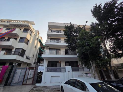 une voiture blanche garée devant un immeuble dans l'établissement Shanti sadan, à Noida