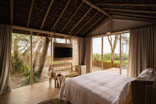 a bedroom with a bed and a large window at Bela Vista Hotel Boutique in Caraíva