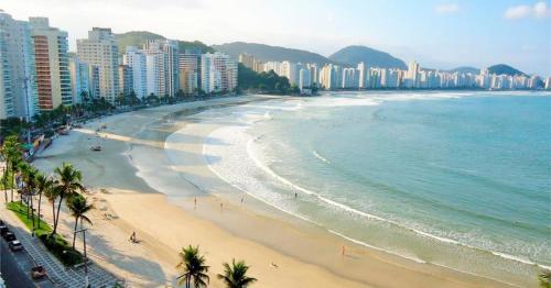 une vue d'une plage avec des bâtiments et l'océan dans l'établissement Linda Cobertura Pitangueiras, à Guarujá
