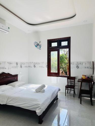 a white bedroom with a bed and a window at Nutty Village Phu Quoc in Phú Quốc