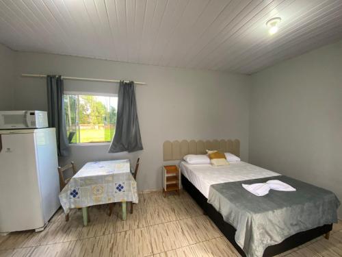 een slaapkamer met 2 bedden, een koelkast en een raam bij Hospedagem estação in Morretes