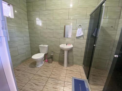 een badkamer met een toilet, een wastafel en een douche bij Hospedagem estação in Morretes