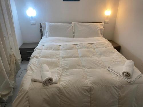 ein Bett mit weißen Laken und Handtüchern darauf in der Unterkunft Appartamento Premier in Gatteo a Mare