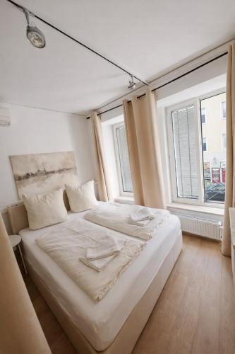 a white bed in a room with two windows at Munich Premium Guesthouse-2 in Munich