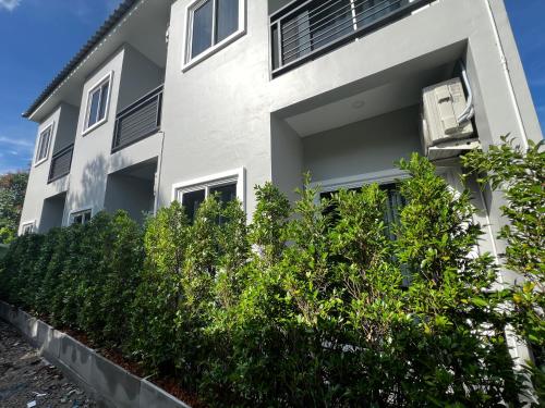 a white building with bushes in front of it at Sarona House 4 in Ban Thalat Choeng Thale