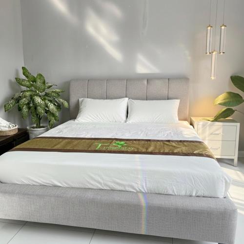 um quarto com uma cama grande com lençóis brancos em T-Homestay Bình minh xanh 