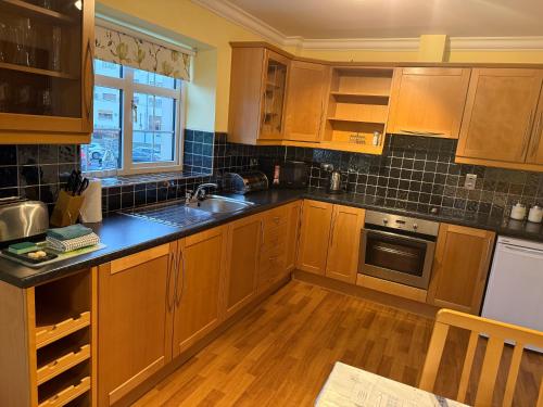a kitchen with wooden cabinets and a sink and a window at 36 Flesk River Apartment in Killarney