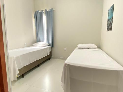 a small room with two beds and a window at Pousada Âncora in Gravataí