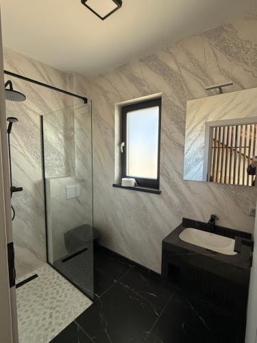 een badkamer met een wastafel en een glazen douche bij California Home in Odoreu