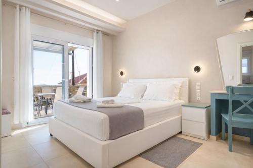 a white bedroom with a bed and a balcony at villa Silda in Atsoupádhes