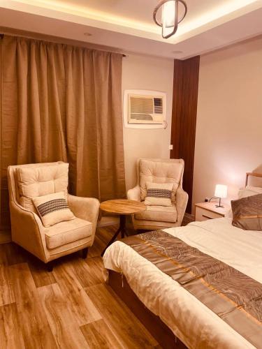 ein Schlafzimmer mit einem Bett und zwei Stühlen und einem Tisch in der Unterkunft روف جازان ذات التصميم الفندقي in Dschāzān