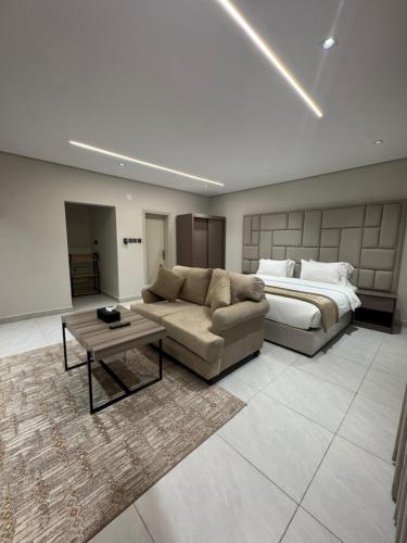 een slaapkamer met een bed, een bank en een tafel bij شقق طلال الفندقية- Talal hotel apartments in Al Ula