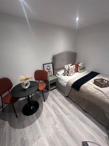 a bedroom with a bed and a table and chairs at Exclusive, newly built detached garden studio, private and self-contained, within family home grounds in Swanscombe