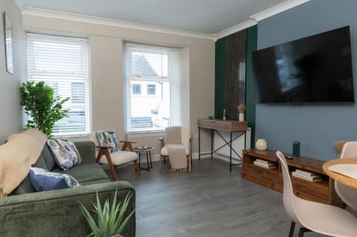 een woonkamer met een bank en een flatscreen-tv bij Vacant Nests Ivy Cottage 3BR Wi-Fi in Banton