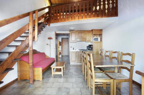 une cuisine et une salle à manger avec un escalier, une table et des chaises dans l'établissement Résidence Odalys Le Front de Neige, aux Carroz d'Arâches