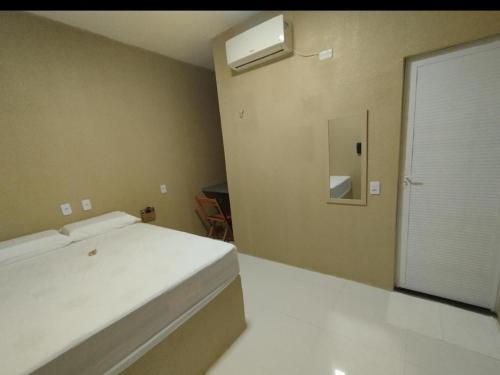 QuixeramobimKarajás Hotel的一间卧室设有一张床、一个窗口和一面镜子