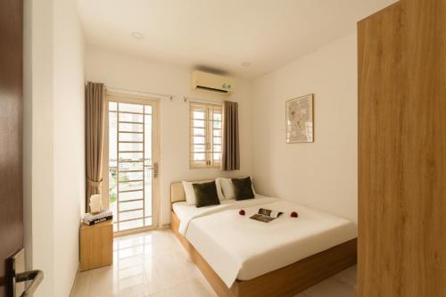 a white bedroom with a bed and a window at The Hammond Saigon in Ho Chi Minh City