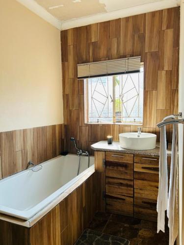 a bathroom with a bath tub and a sink at Bird & Bed Farmhouse in Brits