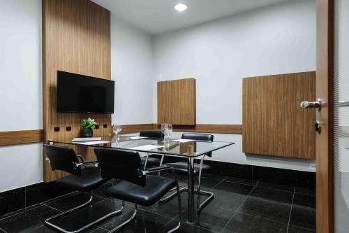 a conference room with a table and chairs and a tv at Vitoria Praia Hotel in Vitória