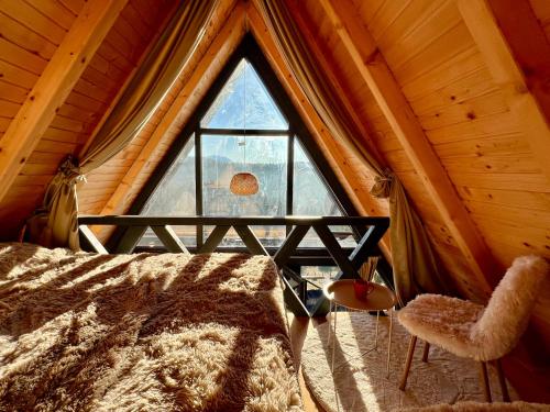 a bedroom with a large window in a cabin at Vikendica Nomadova Koliba in Tvrdimići