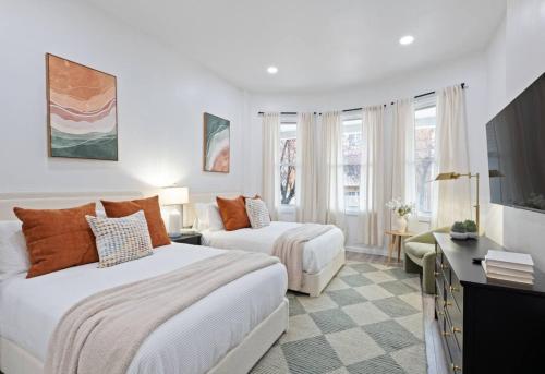 a hotel room with two beds and a television at The Harper Loft near Manhattan with NYC skyline view in Hoboken