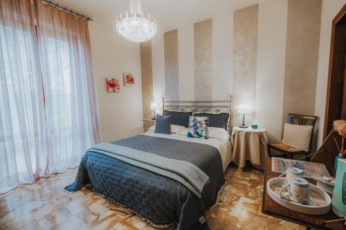 a bedroom with a bed and a chandelier at Affittacamere Casa Mac & Rose in San Quirico dʼOrcia