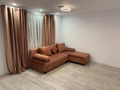 a living room with a brown couch in front of a window at Lad Petite Maison in Craiova