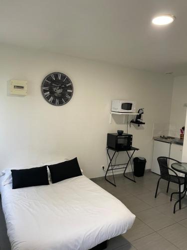 una camera da letto con un letto bianco e un orologio sul muro di Studio Vinci 2 a Calais