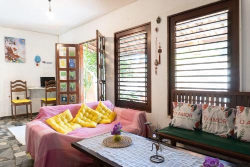 een woonkamer met een roze bank met gele kussens bij Pousada Rose in Pipa