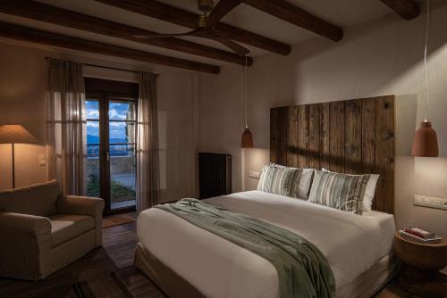 a bedroom with a bed and a chair and a window at Forest Within - Wellness Villa in Archanes in Káto Arkhánai