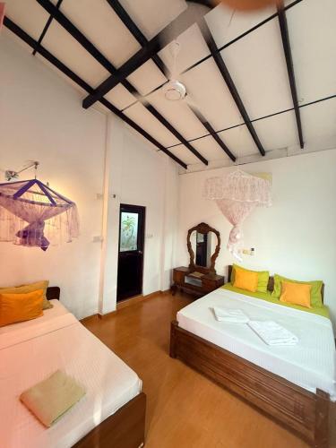 a room with two beds and a mirror at Pearl Deluna Resort Mirissa in Mirissa