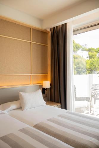 a hotel room with a bed and a window at Hotel Masía Bellver in Benicàssim