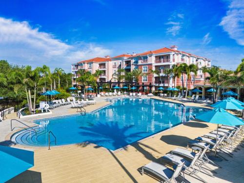 a pool with chairs and umbrellas in a resort at Luxury Lake View Condo-Vista Cay in Orlando