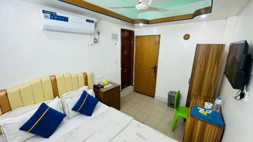 una camera da letto con un letto con cuscini blu e una televisione di Hotel Sweet Place a Gulshan 1
