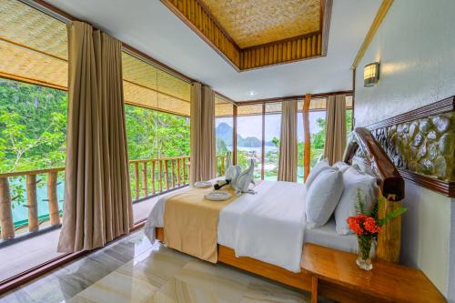 een slaapkamer met een bed en een balkon met ramen bij El Nido Viewdeck Cottages in El Nido