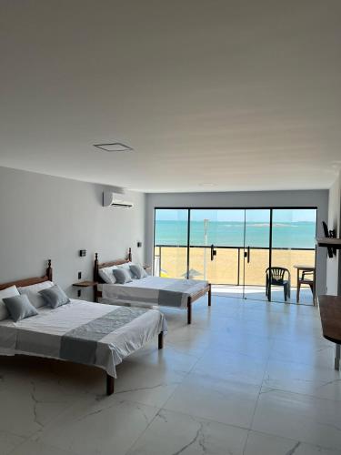 two beds in a room with a view of the beach at Pé na Areia in Guarapari