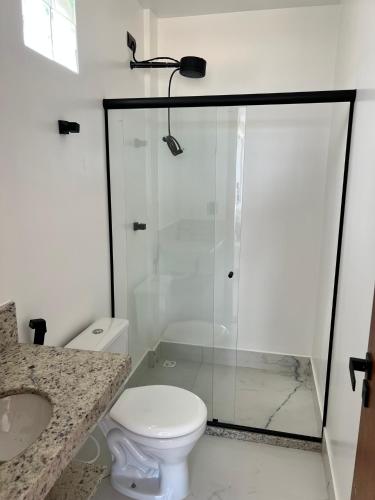 a white bathroom with a shower and a toilet at Pé na Areia in Guarapari