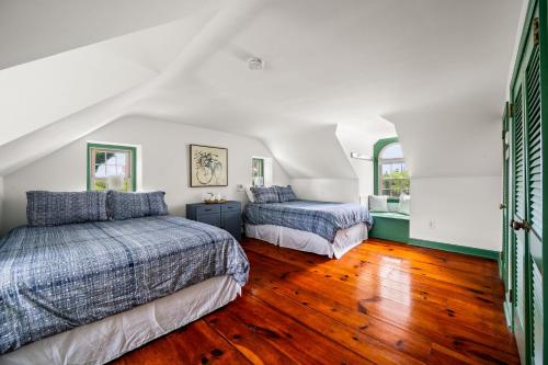 two beds in a room with wood floors and white walls at Downingtown Manor - 1900s Farmhouse with Creek Views in Downingtown