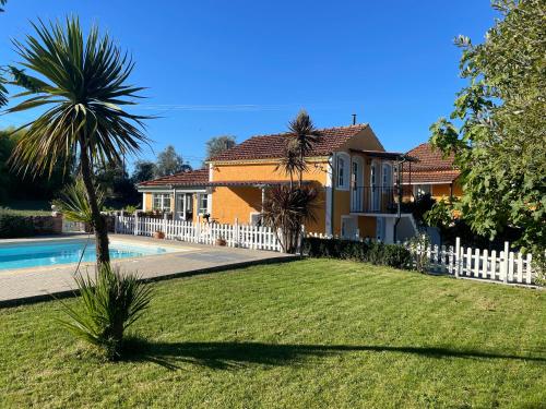 a house with a white fence and a swimming pool at Campos Essencia in Arganil