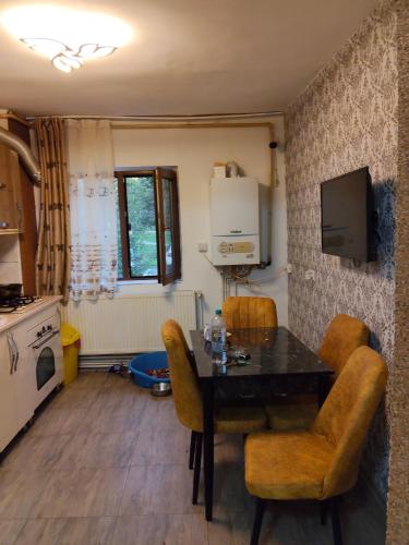 una cucina con tavolo, sedie e televisione di Apartament Gya a Lupeni