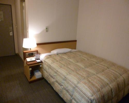 a hotel room with a bed and a table with a lamp at Hotel Crownhills Fukushima in Fukushima